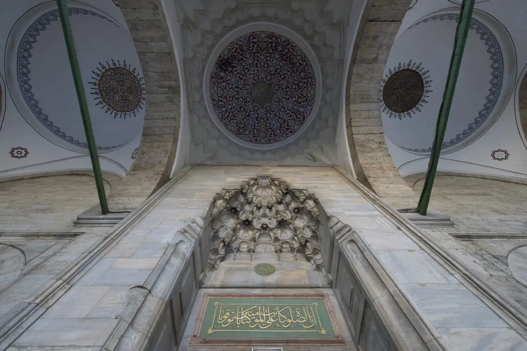 Gazi Atik Ali Paşa Camii'nin cümle kapısı; mukarnaslı niş, üstte kalem işi göbekli kubbeler ve altta yeşil zeminli yazı levhası.