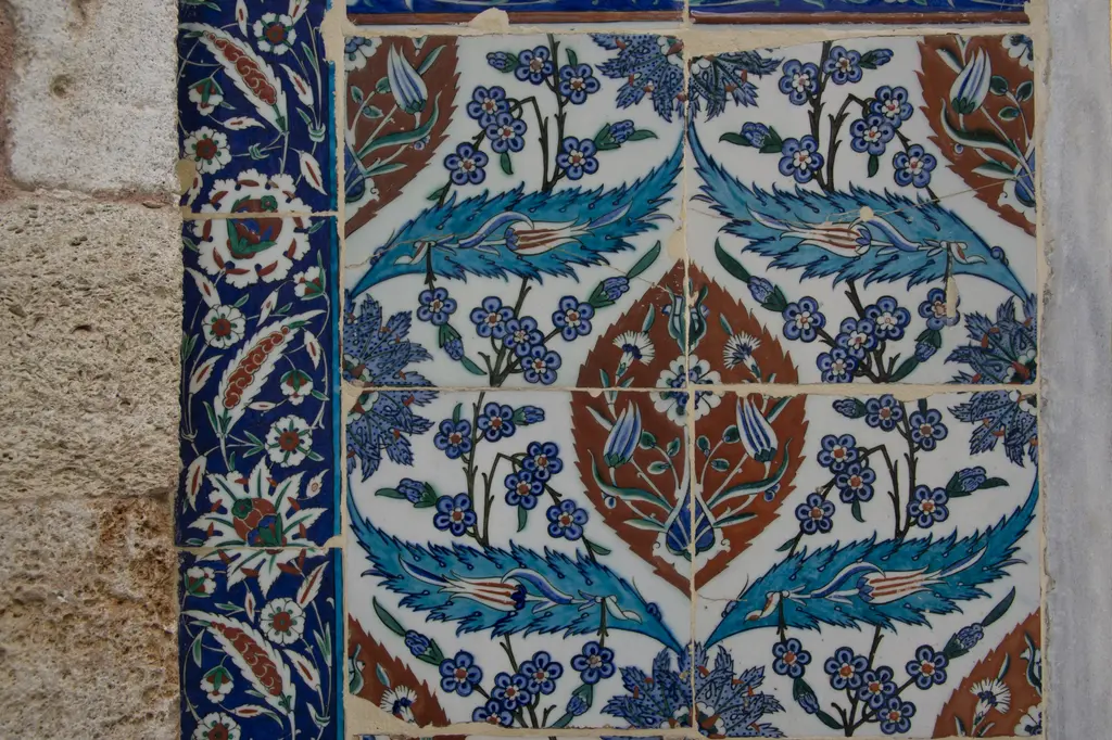 Eyüp Sultan Türbesi'nin dış duvarı; çini kaplamalar, tunç şebekeli büyük pencere, Türk bayrağı ve sıradaki ziyaretçiler.