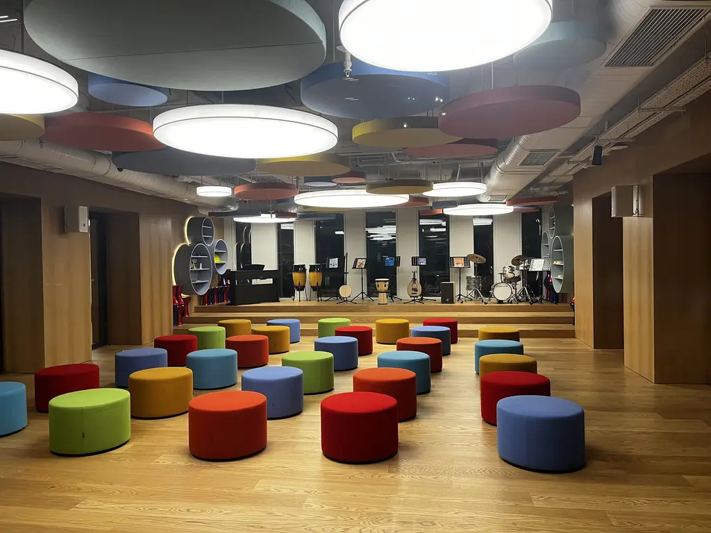 Atatürk Kültür Merkezi'nde bir salon; ahşap zemin, sıra sıra renkli puflar, tavanda yuvarlak aydınlatmalar ve arkada küçük bir sahne.
