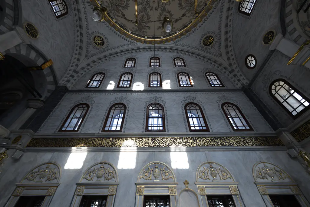 Nusretiye Camii'nin içi; geniş açıyla kemerli pencereler, pandantifler, alt katta sütunlu mahfil ve kubbenin yaldızlı kenarı.