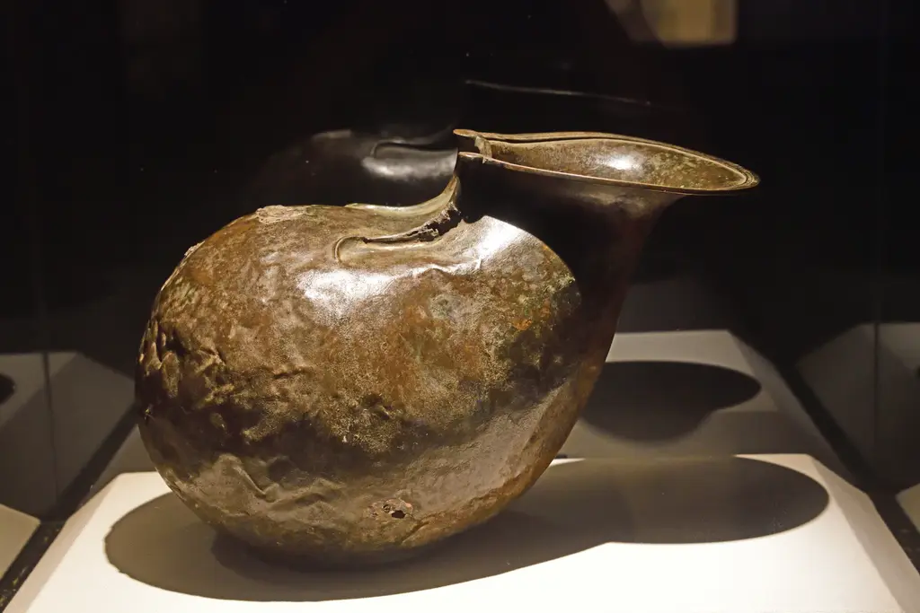 Sadberk Hanım Müzesi'nde Roma dönemi içki kabı; şişkin bronz gövde, yana açılan ağız ve vitrin içindeki beyaz kaide.
