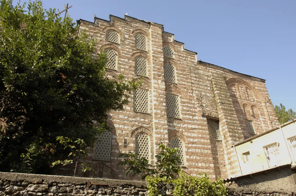 Gül Camii'nin güney cephesi tam güneşte; almaşık örgü sıraları, yüksek kör kemerler, petek gözlü yuvarlak pencereler ve kademeli saçak.