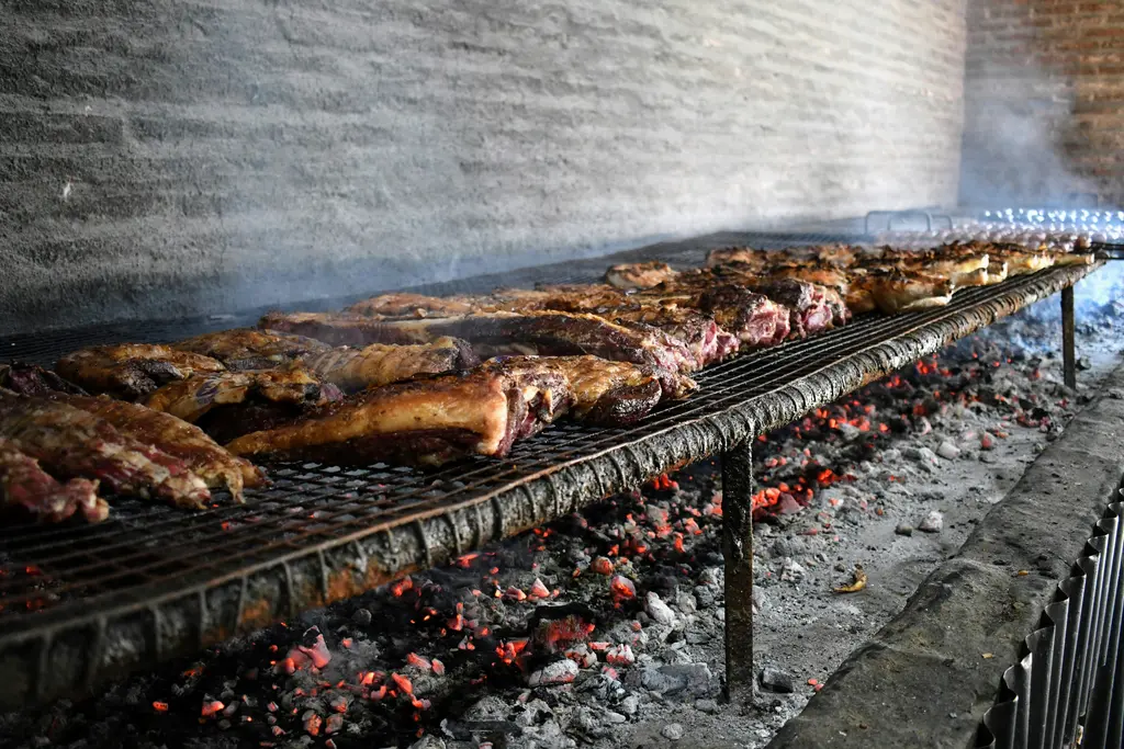 Arjantin usulü asado; kor hâlindeki kömürün üzerindeki geniş ızgarada uzun uzun pişen et parçaları.