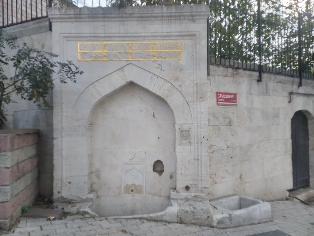 Kösem Sultan Çeşmesi; kesme taş cephe, sivri kemerli niş, üstte yazı levhası ve yanında taş duvar.