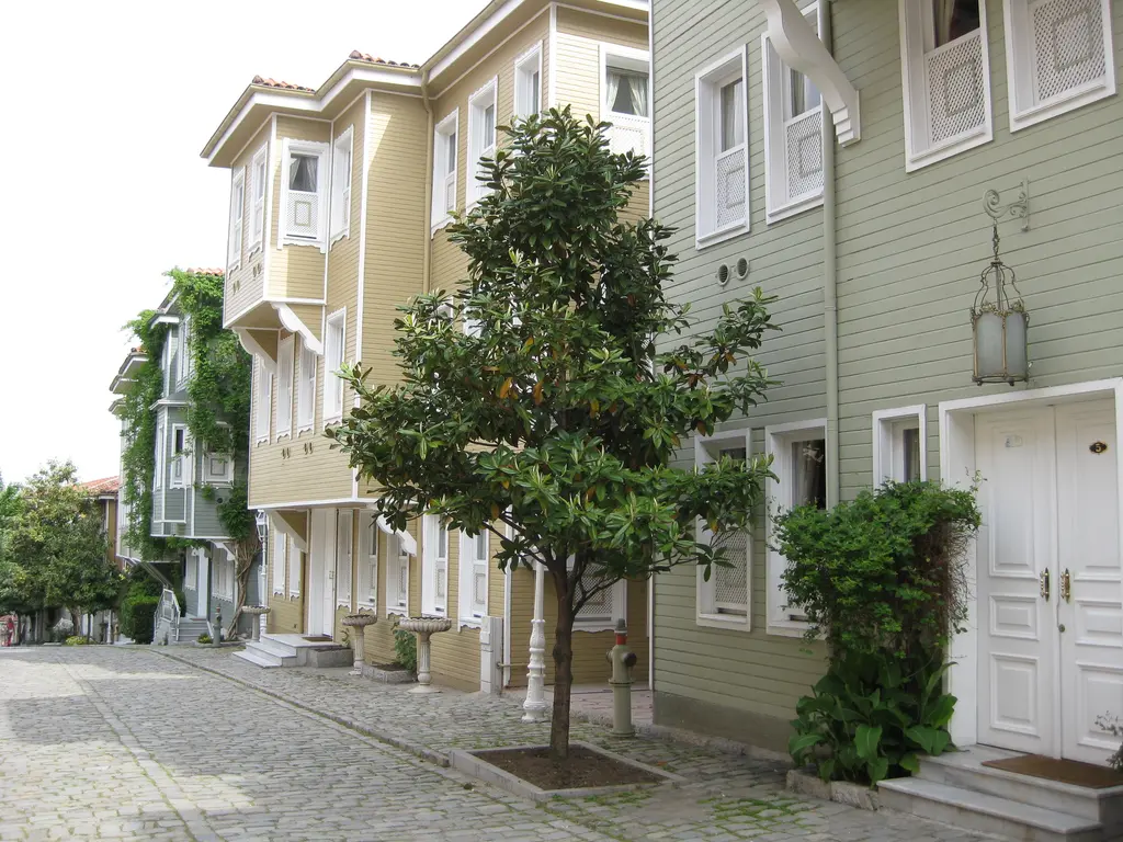 Sultanahmet'te Soğukçeşme Sokağı; iki yanda pastel boyalı ahşap konaklar, cumbalar, kaldırımdaki tek ağaç ve taş döşeli dar yol.