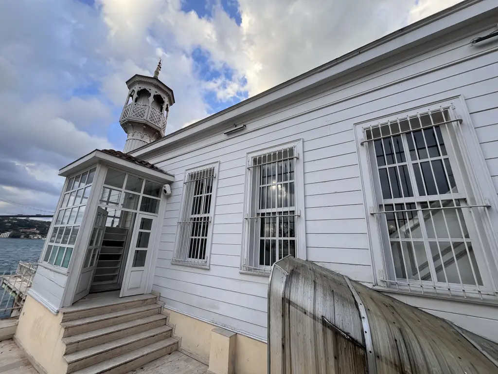 Kuzguncuk'ta Üryanizade Camii; beyaz ahşap gövde, kafesli pencereler, küçük minare ve dar sokak.