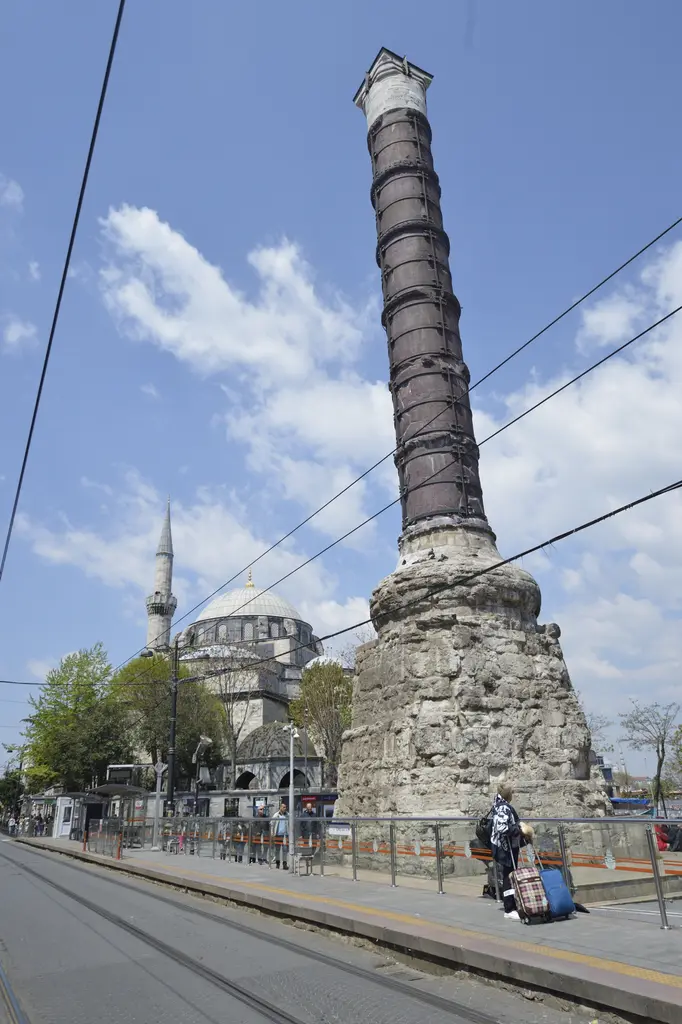 Çemberlitaş'ta sütun ve çevresi; sağda kaideli sütun, solda kubbesi ile tek minaresi görünen cami, önde tramvay rayları.