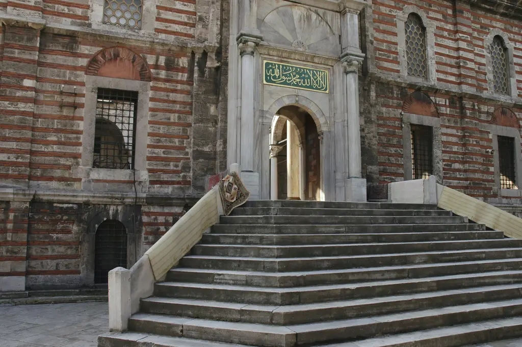 Laleli Camii'nde avlu merdiveni; yukarı çıkan geniş taş basamaklar, iki yanda pilastrlı cephe ve üstte yuvarlak kemerli giriş.
