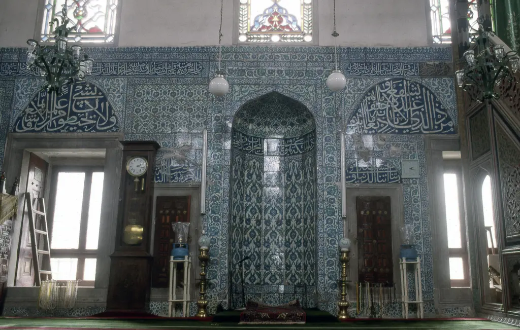Çinili Camii'nde mihrap; mavi ve beyaz çinili niş, iki yanda pencereler, ahşap dolaplar ve şamdanlar.