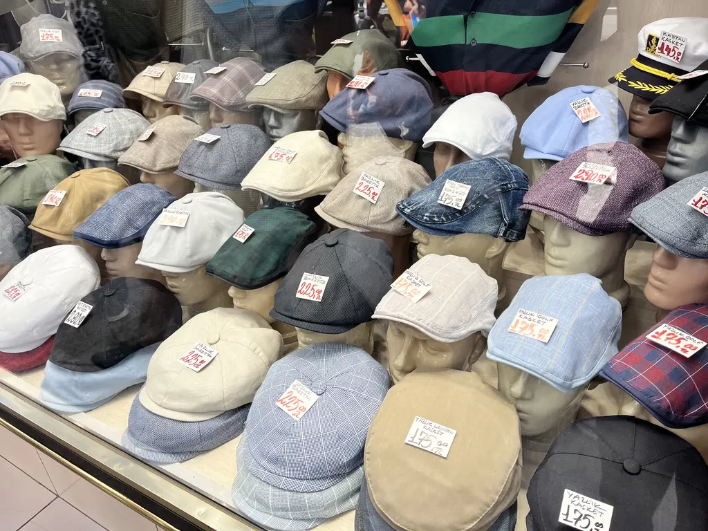 Eminönü'nde şapka vitrini; mankenler üzerinde kasketler, kumaş şapkalar ve fiyat etiketleri.
