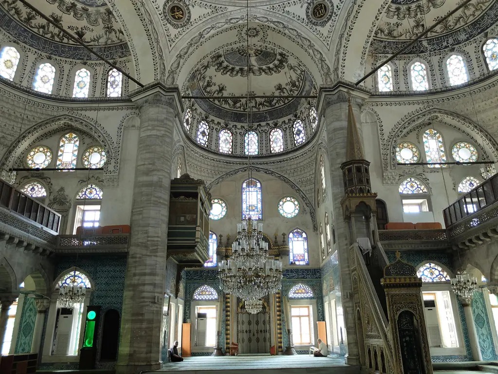 Harimin genel görünüşü; halı kaplı zemin, kemerli mahfil katı, iki yanda çinili duvarlar ve tavandan sarkan avizeler.