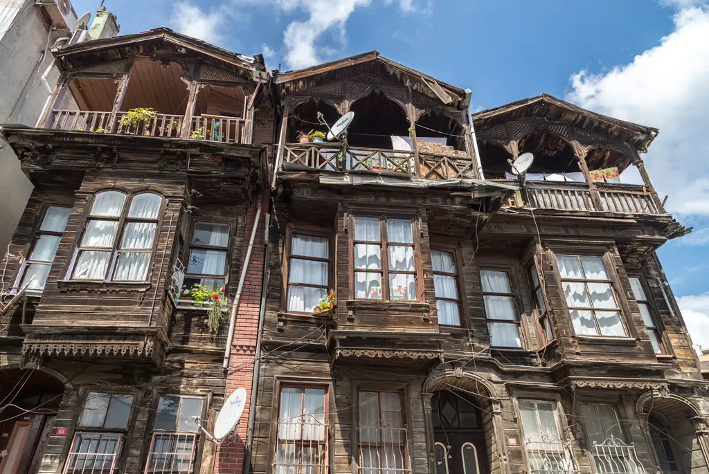 Balat'ta yan yana eski ahşap konaklar; koyu kahverengi cepheler, oymalı balkonlar, cumbalar ve çatıda çanak antenler.