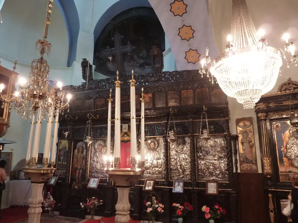 Kanlı Kilise'nin harimi; yanan uzun mumlar, kristal avizeler, gümüş kaplamalı ikonalar ve önlerinde çiçekler bulunan oymalı ikonostasis.