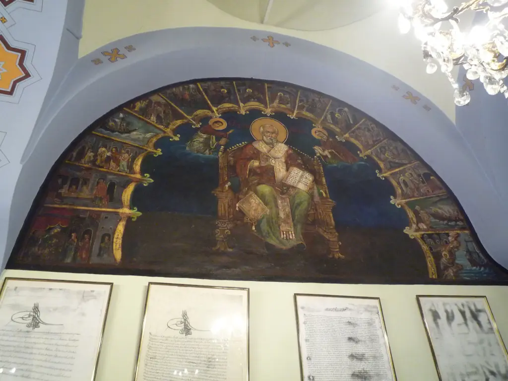 Kanlı Kilise'de yarım daire lunet resmi; tahtta oturan bir aziz, çevresinde küçük sahneler ve altında çerçeveli fermanlar.