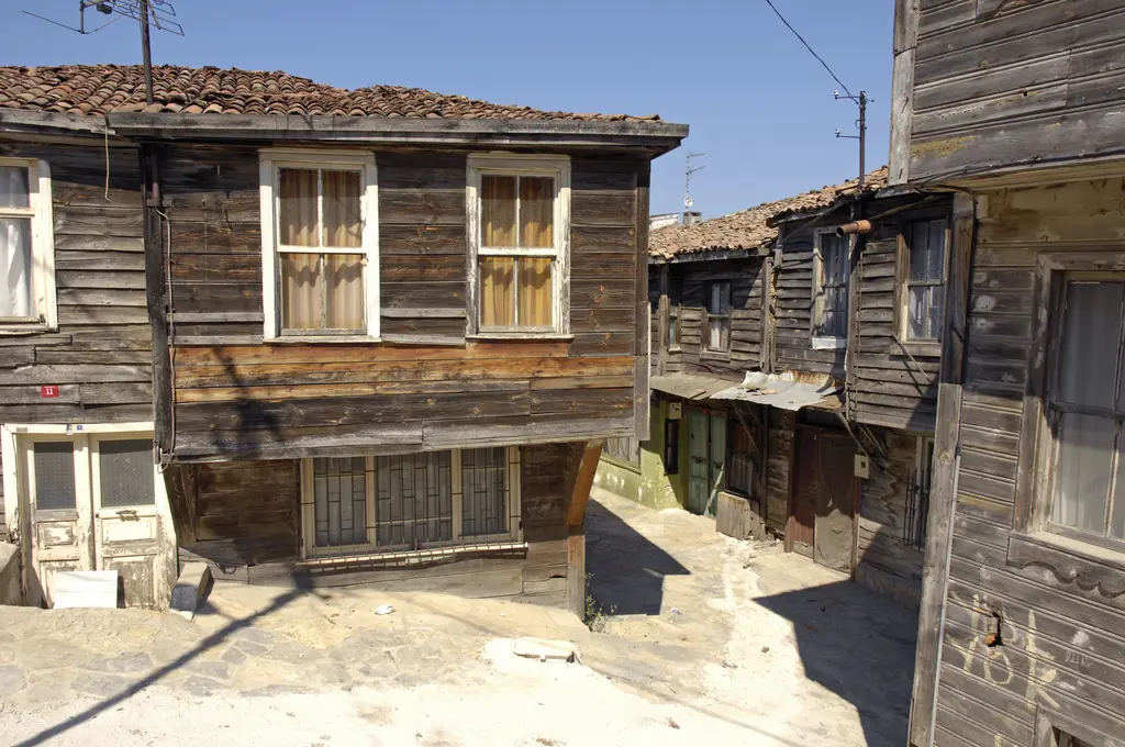 Şile'de eski ahşap evler; yıpranmış tahta cepheli iki katlı evler, çıkmalı pencereler ve taş döşeli dar sokak.