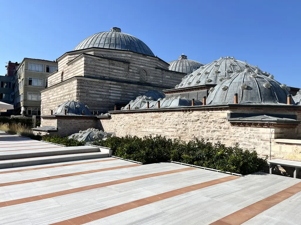 Zeyrek'te Çinili Hamam'ın kubbeleri; terastan bakışta kurşun kaplı büyük soyunmalık kubbesi, yanında fil gözlü sıcaklık kubbeleri ve moloz taş duvar.