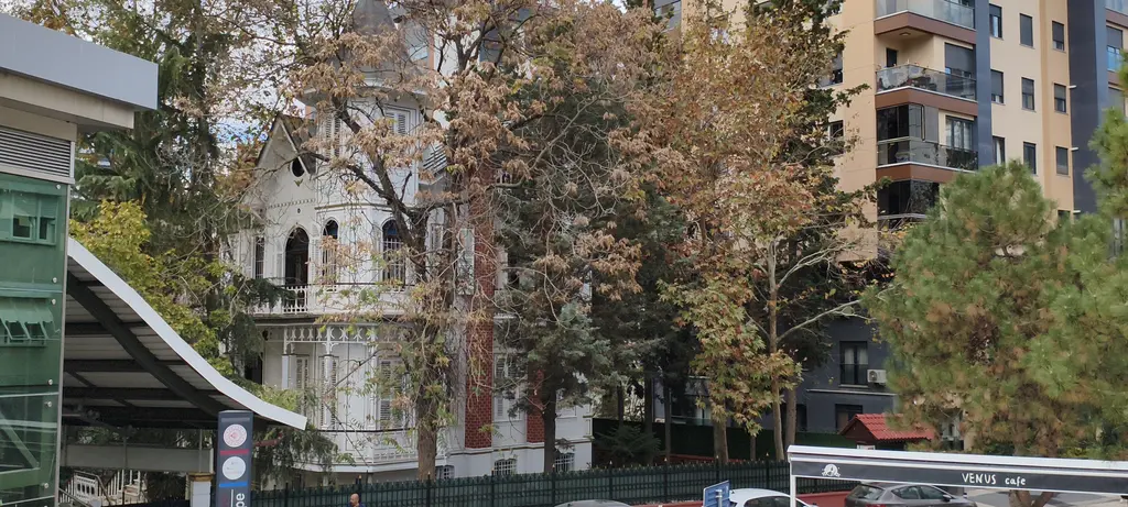 Göztepe'de Galip Paşa Köşkü; ağaçlar arasında sivri çatılı beyaz ahşap köşk, yanında apartmanlar ve cam saçak.
