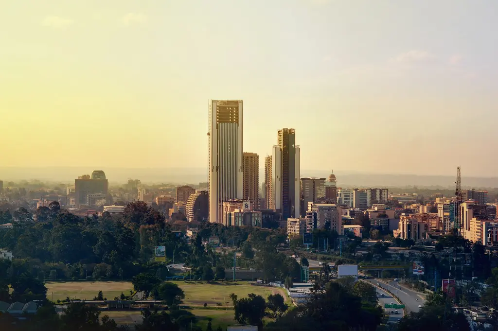 Kenya'nın başkenti Nairobi'nin altın saat ışığındaki silueti; gökdelenler, geniş yeşil park alanları ve ufka doğru uzanan puslu tepeler.