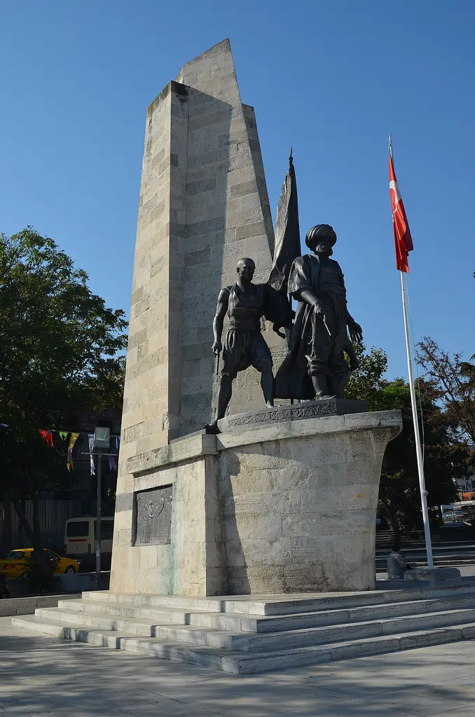 Barbaros Anıtı; basamaklı mermer platform, kademeli taş kaide, bronz heykel grubu ve arkasında yükselen kütle.