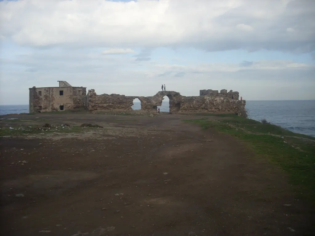 Rumeli Feneri Kalesi; düz bir alanın ortasında yıkık taş surlar, gediklerden görünen deniz ve kapalı gökyüzü.