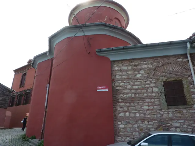 Fener'de Kanlı Kilise; kırmızı sıvalı yarım silindir apsis, üstünde yükselen kubbe kulesi, yanında moloz taş ve tuğla duvar ile demir parmaklıklı pencere.