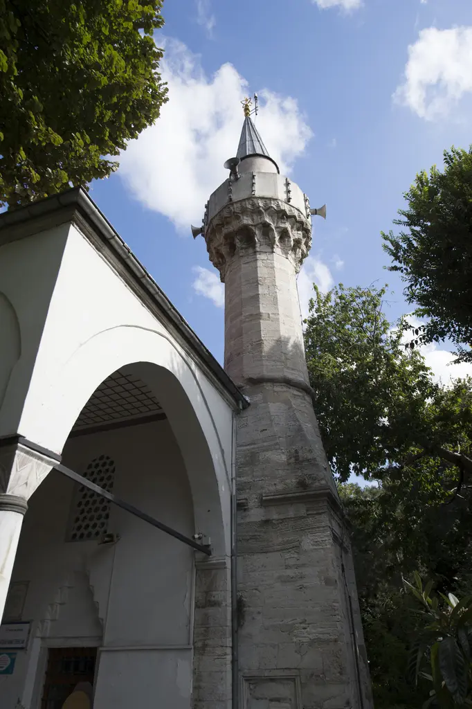 Defterdar Camii'nin minaresi; kesme taş gövde, korkuluklu şerefe, sivri külah ve tepede alem, solda son cemaat kemeri.