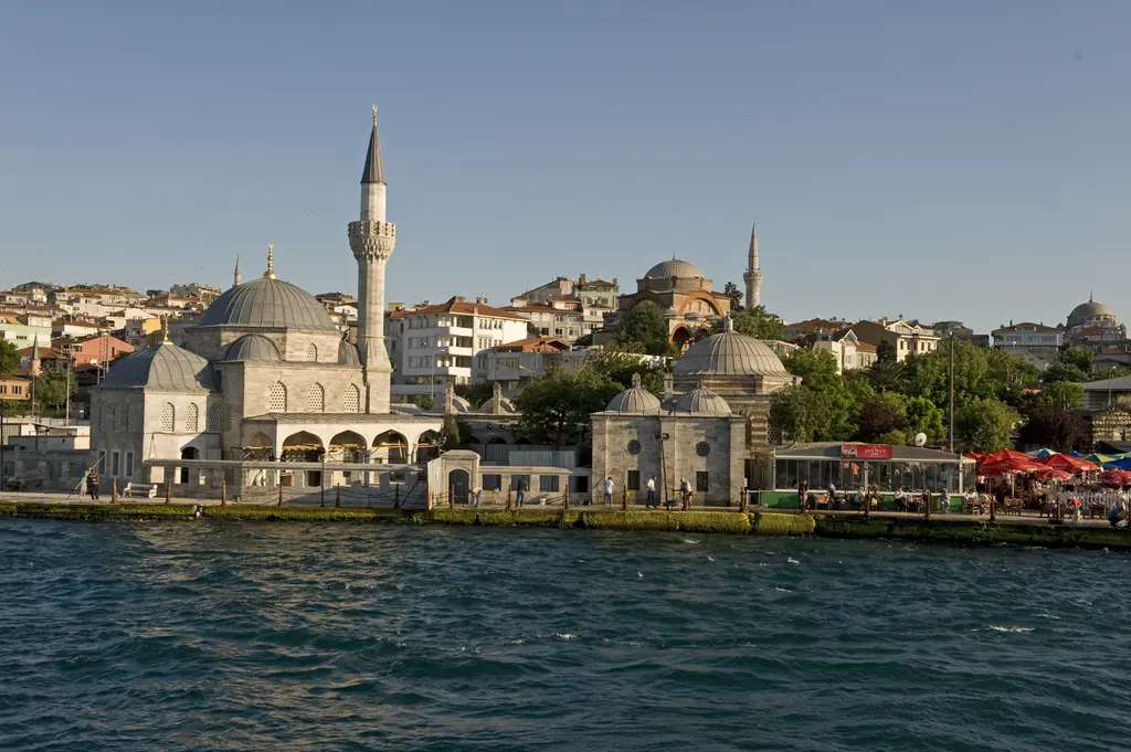 Boğaz'dan Şemsi Paşa Camii; kubbe, minare, medrese kubbeleri ve arkada tepede başka camiler ile evler.