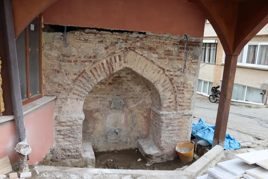 Şile'de Hacı Osman Ağa Çeşmesi; ahşap saçak altında tuğla ve taş örgülü sivri kemerli çeşme nişi ve yalak.