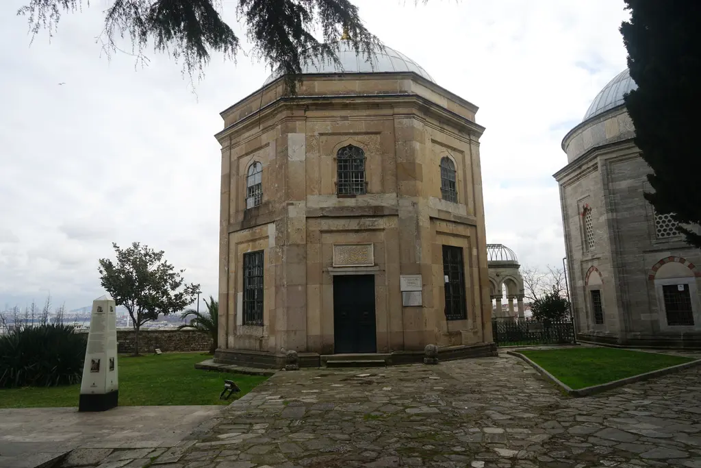 Sultan Abdülmecid Türbesi; kesme taştan sekizgen gövde, kemerli pencereler, çevresinde çimen ve arkada ikinci bir türbe ile serviler.