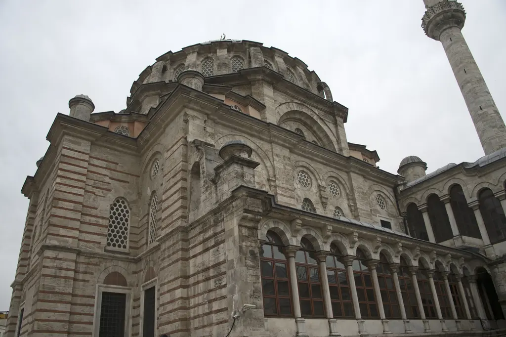 Laleli Camii'nin yandan görünümü; tek büyük kubbe, çevresindeki yarım kubbeler, şeritli duvar örgüsü ve altta yüksek bodrum katının pencere sırası.