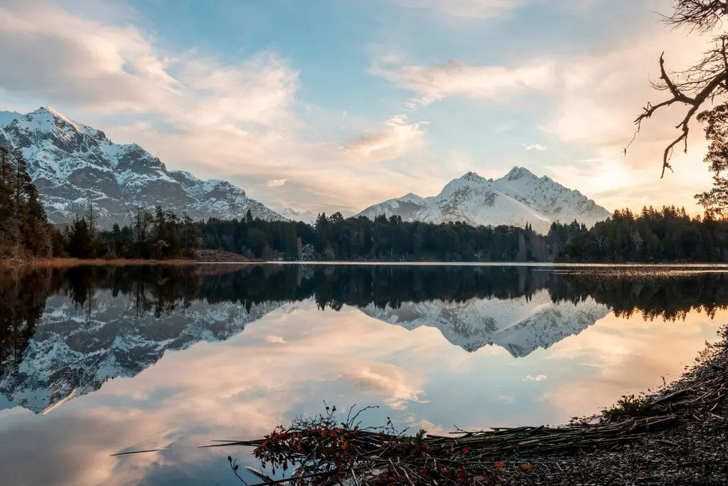 Bariloche'de Nahuel Huapi Gölü; koyu mavi göl, çevresini saran ormanlık dağlar ve kıyı.