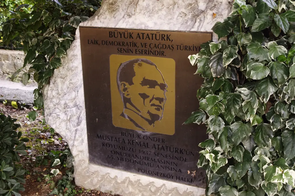 Polonezköy'de beyaz kaya üzerinde sarmaşıklar arasında Atatürk portreli bronz plaket; üstünde "Büyük Atatürk" ile başlayan yazı.