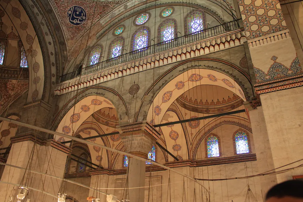 Harimde yukarı bakış; yarım kubbe, altındaki pencere dizisi, korkuluklu mahfil galerisi, renkli camlı pencereler ve kalem işi bezemeler.