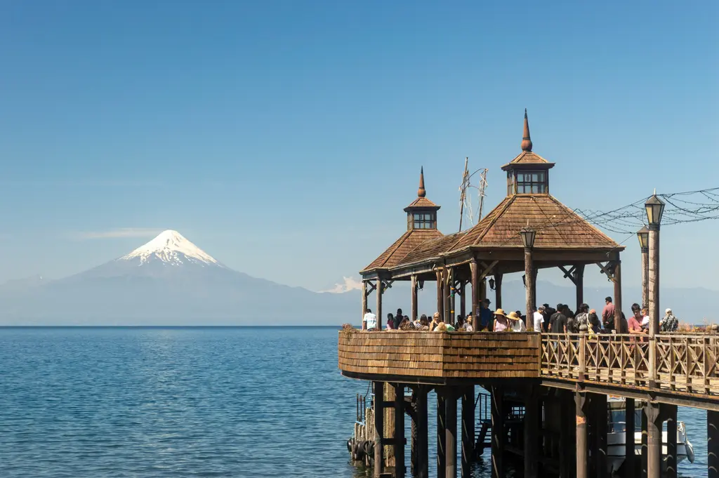 Llanquihue Gölü kıyısında Frutillar'ın ahşap iskele köşkü ve suyun karşısındaki karlı Osorno Yanardağı konisi.