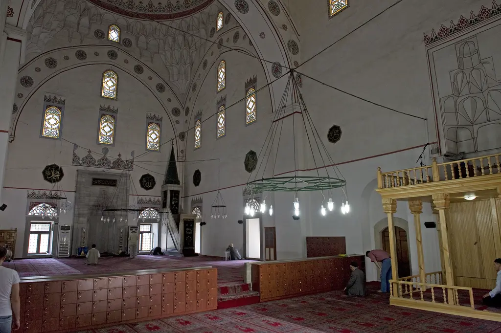 Murat Paşa Camii'nin içi; beyaz duvarlar, kemerli pencereler, kalem işli kubbe eteği, avize halkası ve ahşap vaaz kürsüsü.