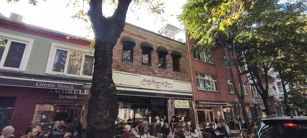 Kuzguncuk'ta tarihi fırın ve lokantalar; tuğla ve renkli cepheler, tenteli vitrinler, önde çınar ve sokak masaları.