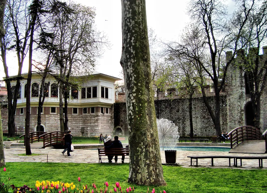 Gülhane Parkı'ndan Alay Köşkü'nün kanadı; sur üstünde pencereli beyaz yapı, önde havuz ve fıskiye, banklar, çınar ve lale tarhı.