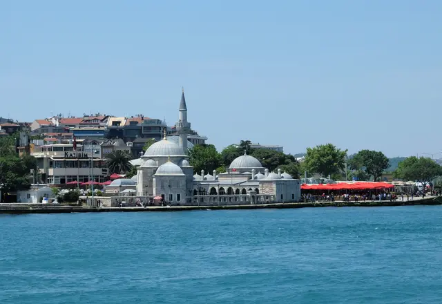 Üsküdar'da Şemsi Paşa Camii; deniz kenarında kubbe, tek minare, medrese kubbeleri ve önde mavi Boğaz suyu.