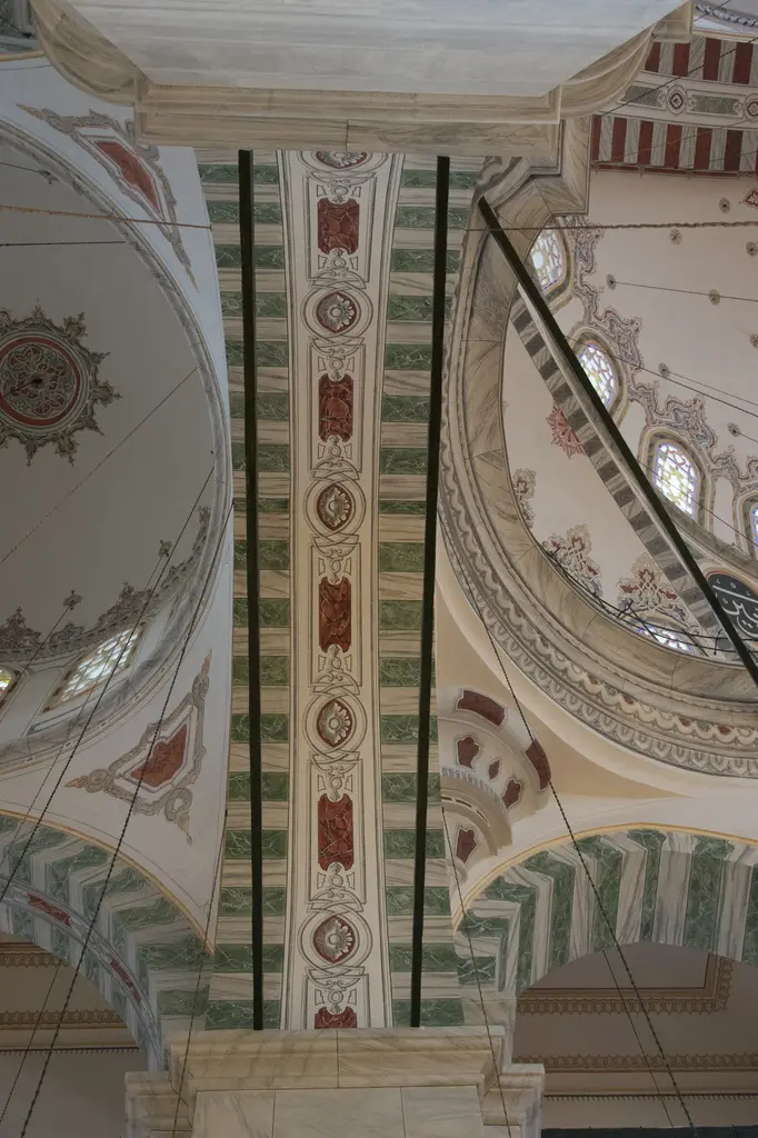 Fatih Camii'nde iki kubbenin birleştiği yere bakış; geniş kemer bandında yeşil, kiremit kırmızısı ve krem kalem işi zikzaklar, çiçek rozetleri ve kartuşlar.