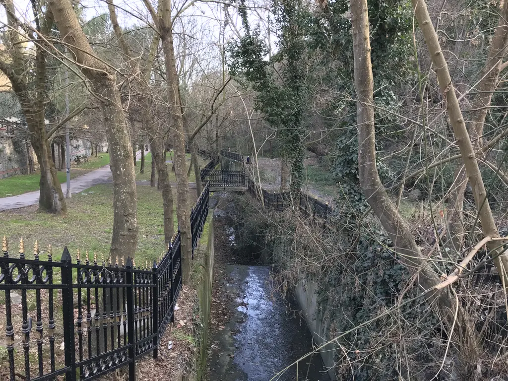 Tarabya Deresi; ağaçlar arasında akan dar dere, kıyısında demir korkuluk ve yürüyüş yolu.
