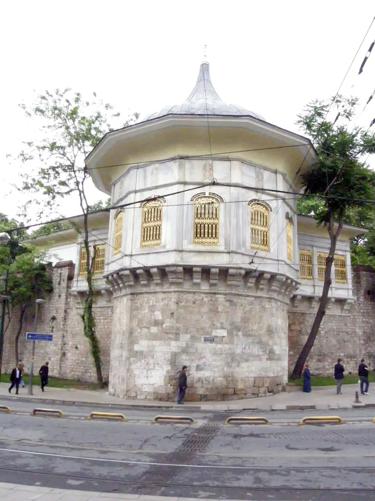 Cadde köşesinden Alay Köşkü; yuvarlak burç üstünde mermer salon, soğan kubbe, sur boyunca uzanan kanat ve iki yanda yeşil ağaçlar.