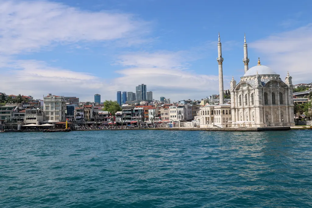 Denizden Ortaköy; kıyıya dizilen kafeler ve binalar, sağda kubbeli cami ve minareleri, arkada Levent'in yüksek binaları.