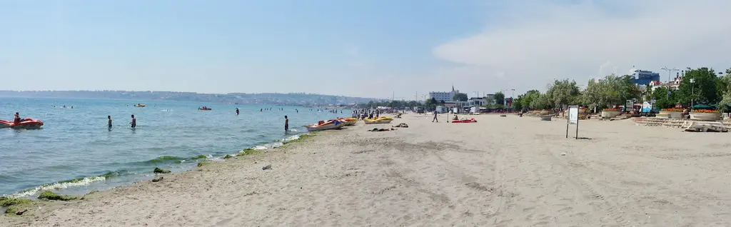 Büyükçekmece'de plaj; uzun düz kumsal, denize girenler, kıyıdaki ağaçlar ve sakin deniz.