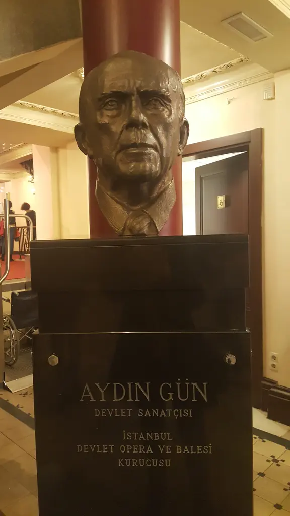Süreyya Operası'nda tenor Aydın Gün'ün büstü; bronz baş, yazılı kaide ve kırmızı ahşap duvar.