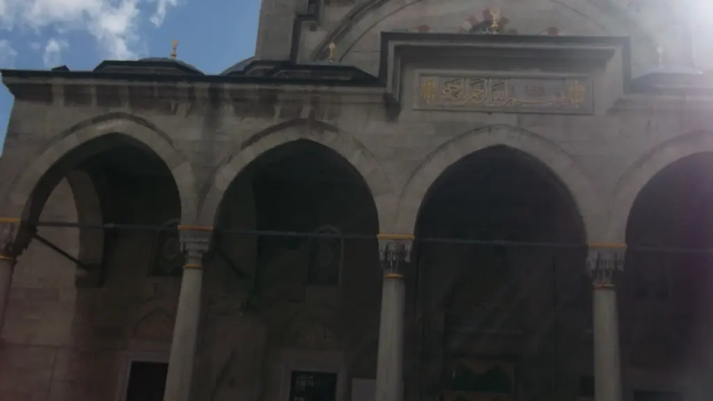 Şişli Camii'nin revak kemerlerine yakın bakış; taş kemerler, sütun başlıkları, kitabe panosu ve arkada kubbe.