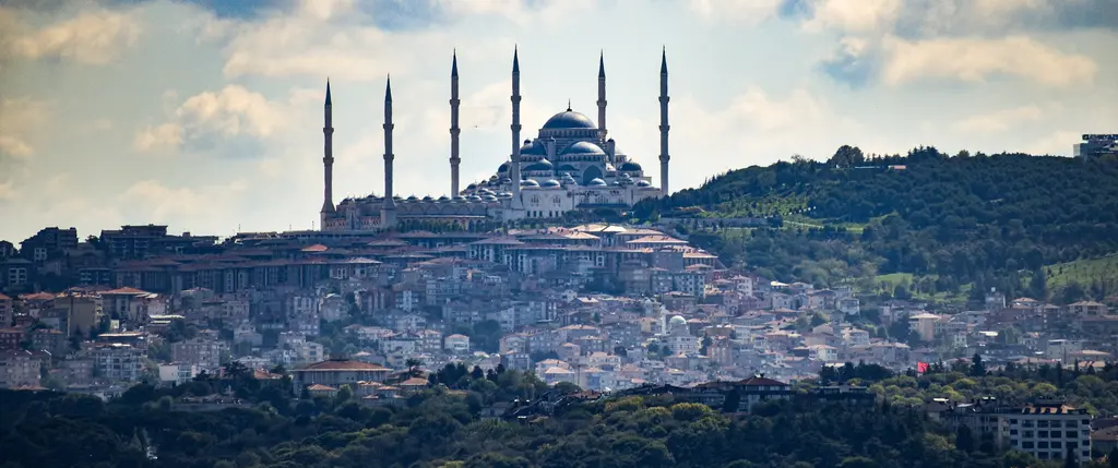 Uzaktan Büyük Çamlıca Camii; ufukta tepe üstündeki altı minareli cami, önünde Üsküdar'ın yamaçları.
