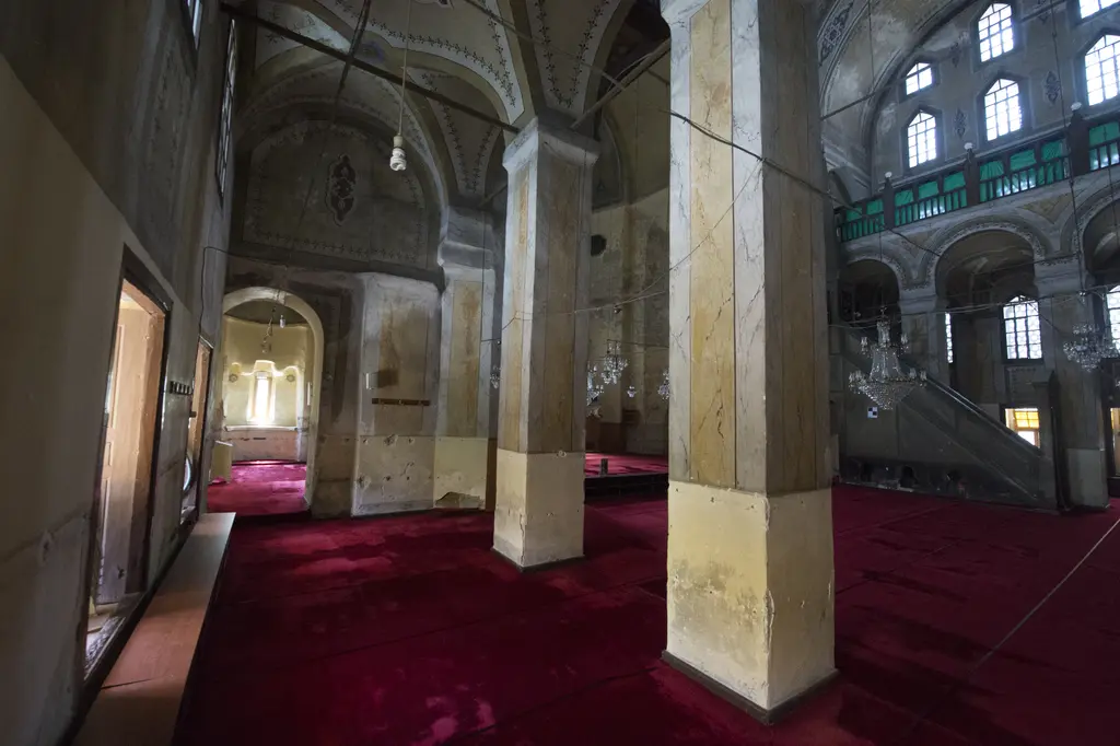 Gül Camii'nin kuzey yan nefi; mermer taklidi boyalı masif payeler, tonozlu bölümler, kırmızı halı, sağda galerili ana mekân ve avizeler.