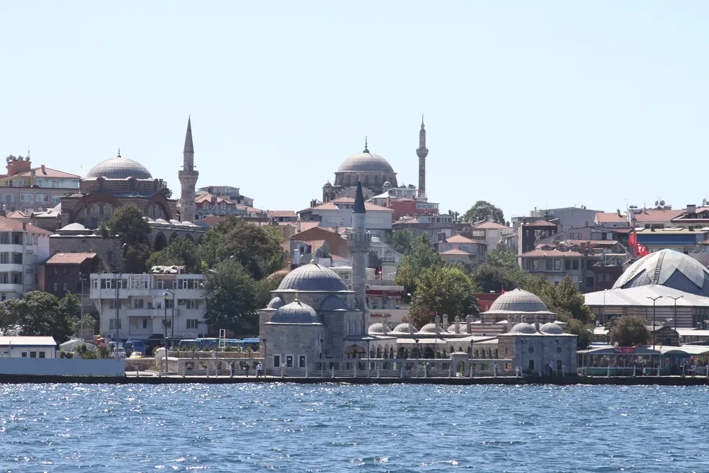 Boğaz'dan Şemsi Paşa Camii; kıyıda küçük kubbeli yapı, arkada yamaçta büyük kubbeli camiler ve evler.