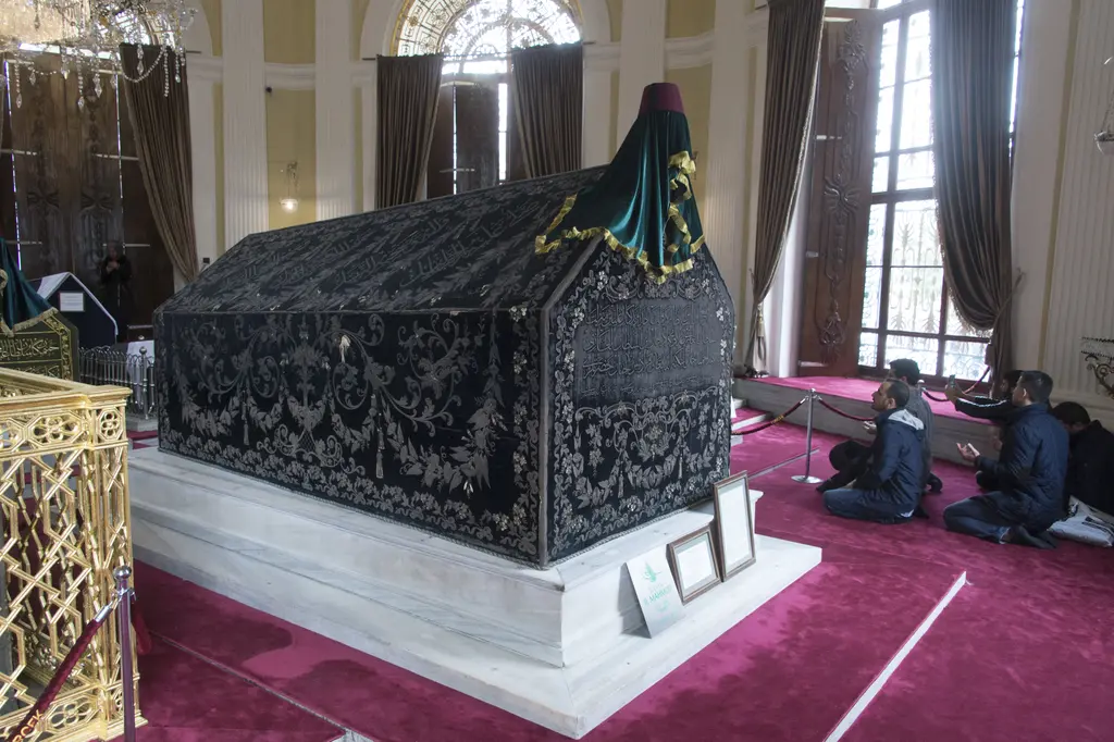 II. Mahmud Türbesi'nde büyük bir padişah sandukası; sırma işlemeli siyah örtü, başında sarıklı yeşil örtü, mermer kaide ve dua eden ziyaretçiler.