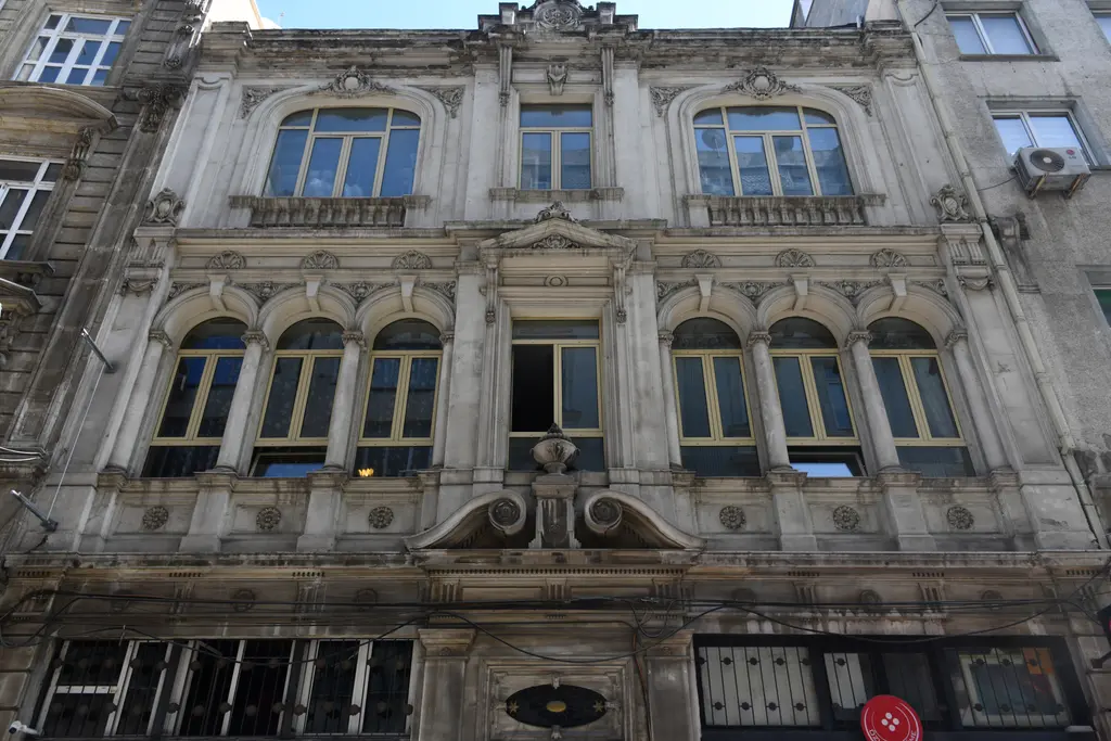 Eminönü'nde eski iş hanının cephesi; taş süslemeli pencere sırası, balkonlar ve alt katta dükkân vitrinleri.